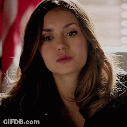 A Woman With Long Brown Hair Is Looking At The Camera GIF