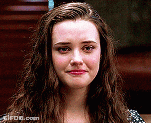 A Woman With Long Brown Hair Is Looking At The Camera With A Sad Look On Her Face . GIF