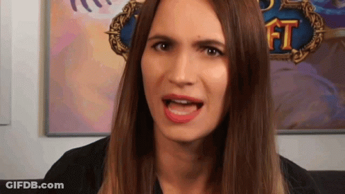 A Woman With Long Brown Hair Is Making A Funny Face In Front Of A Painting Of A Game . GIF
