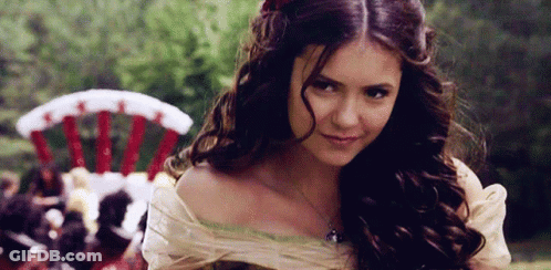A Woman With Long Brown Hair Is Smiling And Looking At The Camera GIF