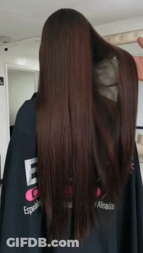 A Woman With Long Brown Hair Is Wearing A Black Cape That Says Especialistas Alisados GIF