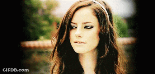 A Woman With Long Brown Hair Wearing A Headband Looks At The Camera GIF