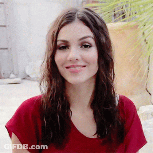 A Woman With Long Brown Hair Wearing A Red Shirt Smiles For The Camera GIF