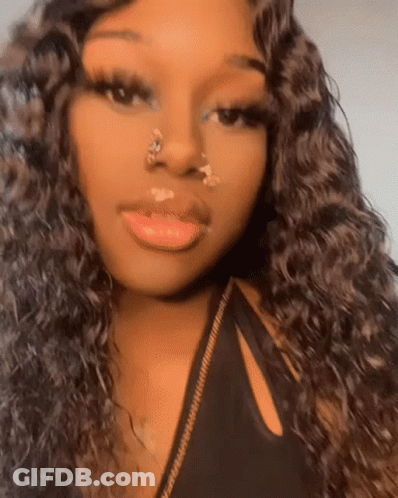 A Woman With Long Curly Hair And A Nose Ring Is Taking A Selfie . GIF