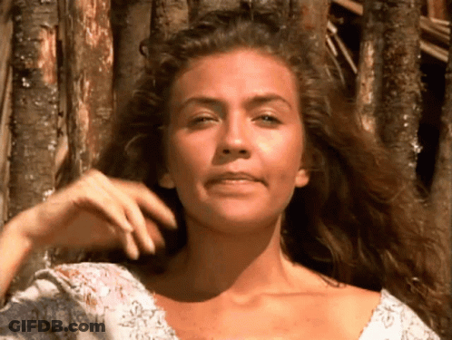 A Woman With Long Curly Hair Looks At The Camera GIF