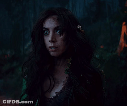 A Woman With Long Dark Hair And Feathers In Her Hair GIF