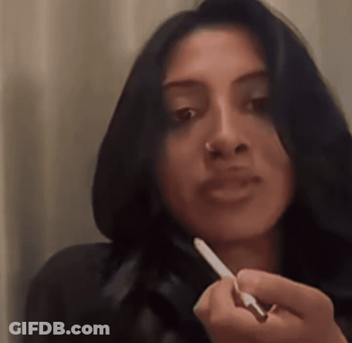 A Woman With Long Dark Hair Is Holding A Pen In Her Hand GIF