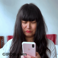 A Woman With Long Dark Hair Is Holding A Pink Iphone In Her Hand . GIF