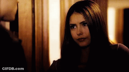 A Woman With Long Dark Hair Is Looking At A Man In A Doorway . GIF
