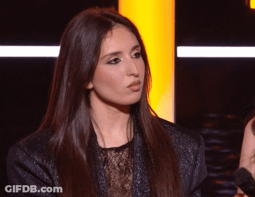 A Woman With Long Dark Hair Is Looking At The Camera GIF