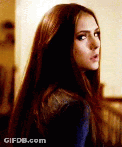 A Woman With Long Dark Hair Is Looking Over Her Shoulder . GIF