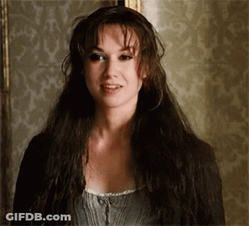 A Woman With Long Dark Hair Is Standing In Front Of A Wall . GIF