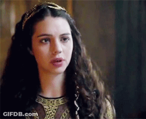 A Woman With Long Dark Hair Is Wearing A Headband And A Crown . GIF