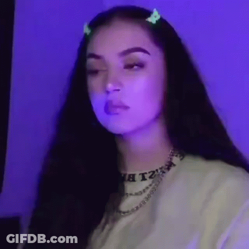 A Woman With Long Dark Hair Is Wearing A Necklace And A Hair Clip . GIF