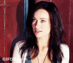 A Woman With Long Dark Hair Is Wearing A White Cardigan GIF