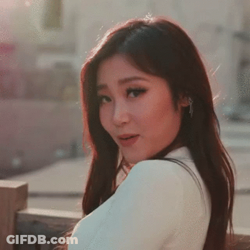 A Woman With Long Dark Hair Is Wearing A White Shirt GIF