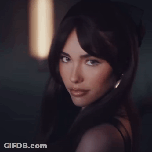 A Woman With Long Dark Hair Looks At The Camera GIF