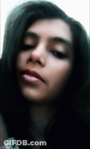 A Woman With Long Dark Hair Looks At The Camera GIF
