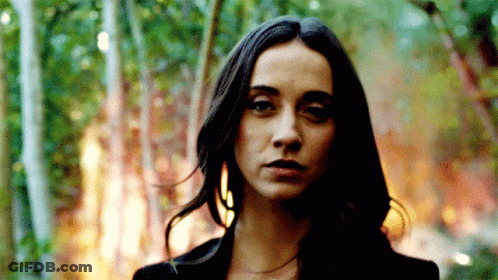 A Woman With Long Dark Hair Stands In Front Of A Forest Fire GIF
