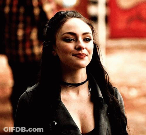 A Woman With Long Dark Hair Wearing A Choker And A Leather Jacket GIF