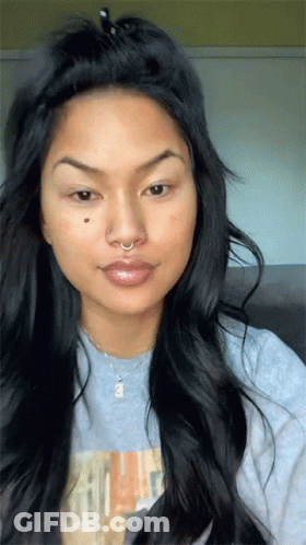 A Woman With Long Hair And A Nose Ring Is Wearing A Grey Shirt GIF