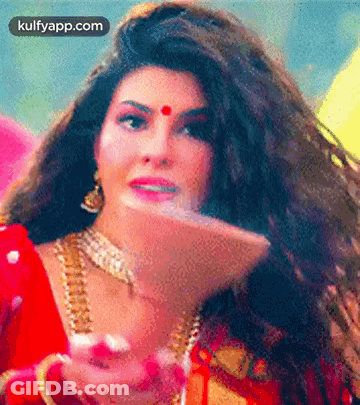 A Woman With Long Hair And A Red Bindi On Her Forehead Is Wearing A Red Dress And Gold Jewelry . GIF