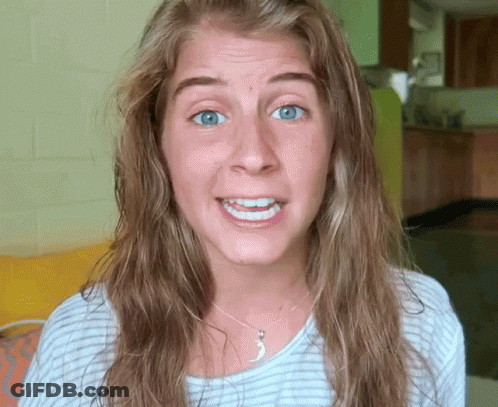A Woman With Long Hair And Blue Eyes Is Smiling And Wearing A Necklace GIF