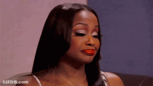 A Woman With Long Hair And Red Lipstick Is Sitting On A Couch . GIF