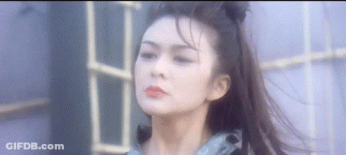 A Woman With Long Hair In A Ponytail Is Standing In Front Of A Window . GIF