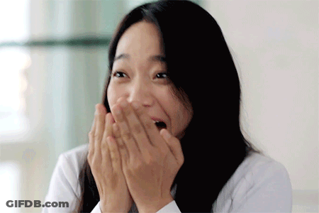 A Woman With Long Hair Is Covering Her Mouth With Her Hands . GIF