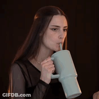 A Woman With Long Hair Is Drinking From A Mug With A Straw . GIF