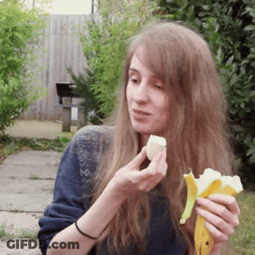 A Woman With Long Hair Is Eating A Banana Peel GIF