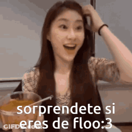 A Woman With Long Hair Is Holding A Glass Of Orange Juice And Making A Funny Face . GIF