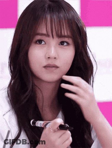 A Woman With Long Hair Is Holding A Marker In Her Hand And Looking At The Camera . GIF