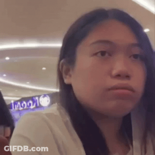 A Woman With Long Hair Is Making A Funny Face While Sitting In A Restaurant . GIF