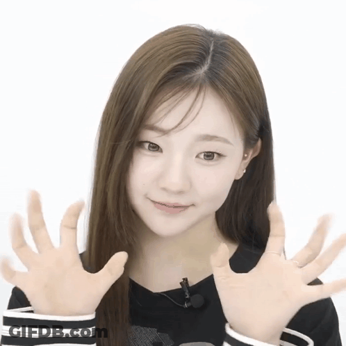 A Woman With Long Hair Is Making A Funny Face With Her Hands In Front Of Her Face GIF