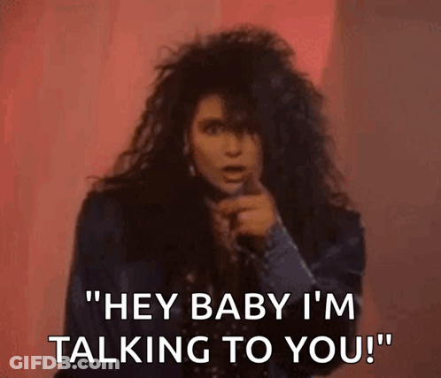 A Woman With Long Hair Is Singing Into A Microphone And Says `` Hey Baby I 'M Talking To You '' . GIF