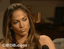 A Woman With Long Hair Is Sitting In Front Of A Microphone And Looking At The Camera . GIF