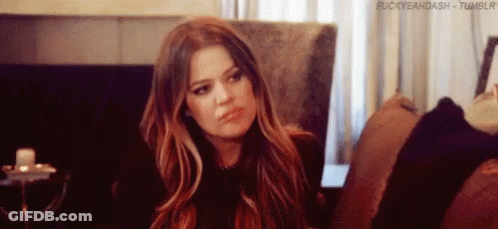 A Woman With Long Hair Is Sitting On A Couch And Making A Funny Face . GIF