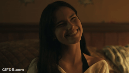 A Woman With Long Hair Is Smiling And Looking At The Camera GIF