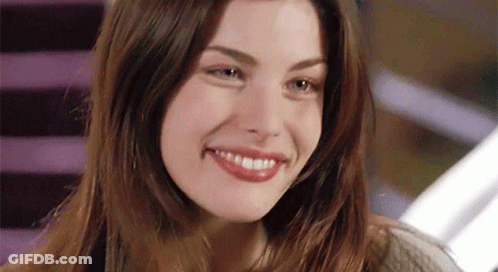 A Woman With Long Hair Is Smiling And Looking At The Camera GIF