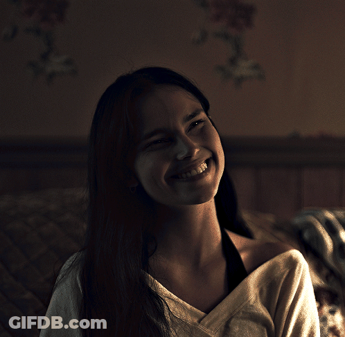 A Woman With Long Hair Is Smiling And Looking Up At The Camera GIF
