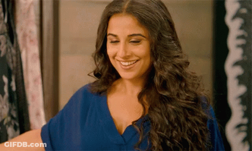 A Woman With Long Hair Is Smiling And Wearing A Blue Dress GIF