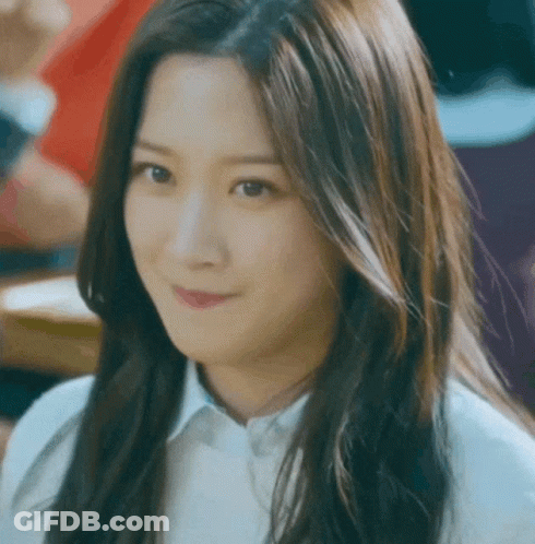 A Woman With Long Hair Is Smiling And Wearing A White Shirt GIF