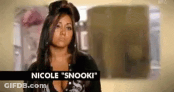 A Woman With Long Hair Is Standing In A Room With A Sign That Says Nicole Snooki . GIF