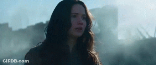 A Woman With Long Hair Is Standing In Front Of A Building In A Field . GIF