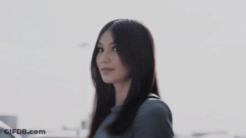 A Woman With Long Hair Is Standing In Front Of A Car And Smiling . GIF