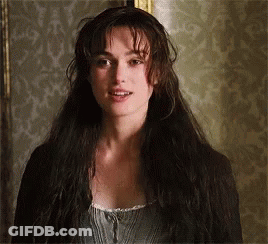 A Woman With Long Hair Is Standing In Front Of A Wall . GIF