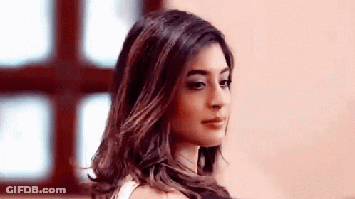 A Woman With Long Hair Is Standing In Front Of A Window Looking At The Camera . GIF