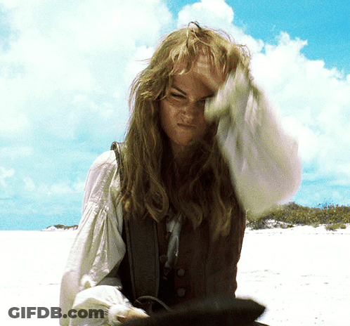 A Woman With Long Hair Is Standing On A Beach With Her Hand On Her Head GIF